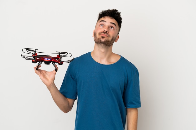 Man holding a drone isolated on white background and looking up