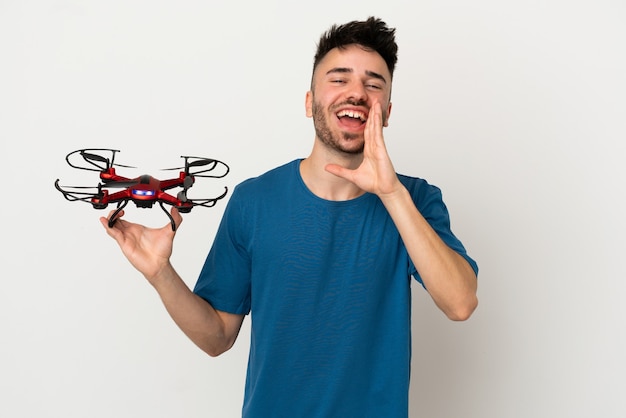 Man holding a drone isolated on white background shouting with mouth wide open