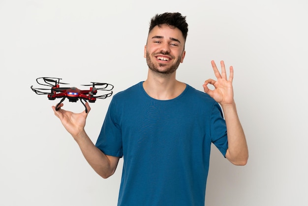 Man holding a drone isolated on white background showing ok sign with fingers