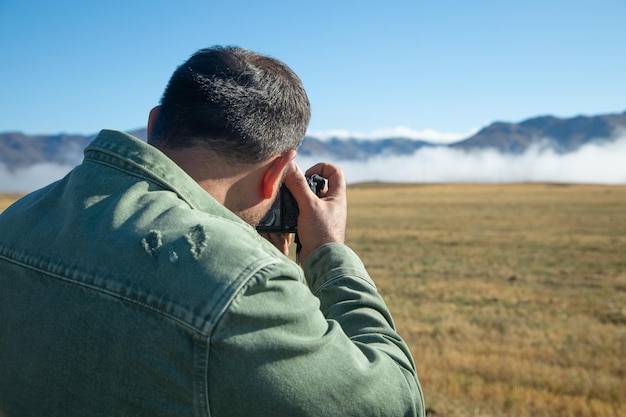 Foto uomo che tiene la fotocamera dslr all'aperto