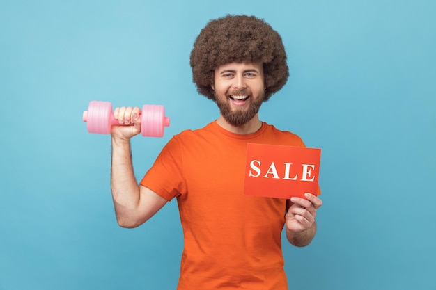 Man holding dumbbell and card with sale inscription sales for fitness workout