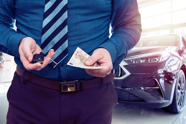 Man holding euro banknote for buy or rent new car at showroom