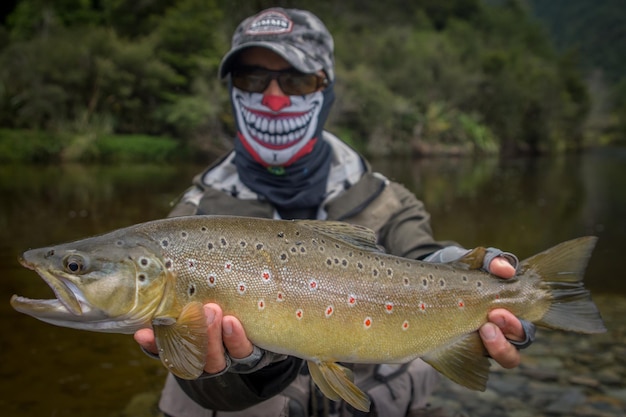 Photo man holding fish against lake