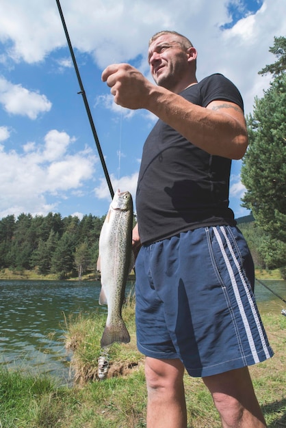 Foto uomo che tiene un pesce sul campo