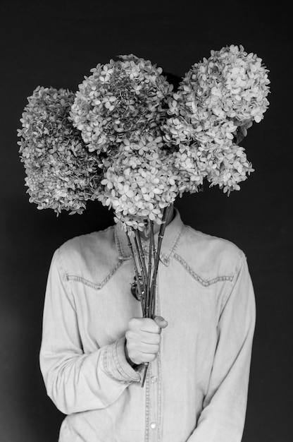 Foto uomo con dei fiori sullo sfondo nero