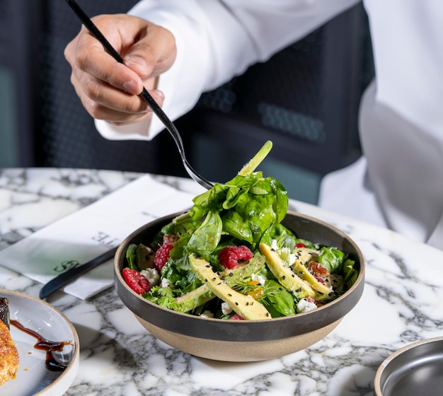 A man holding a fork and eating green salad