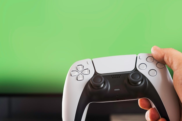 Photo man holding a next generation white game controller isolated on green background. chroma key.