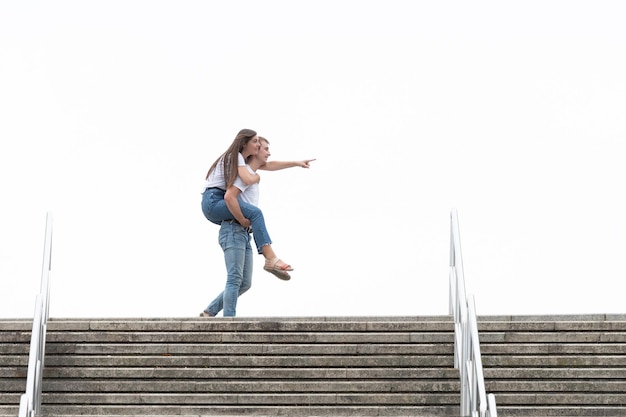 Man holding girlfriend piggyback on the top of a staircase.