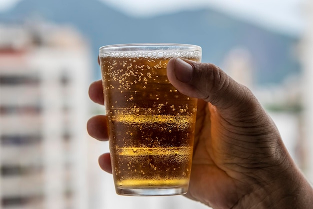 Man holding glass of beer on blurred urban city background