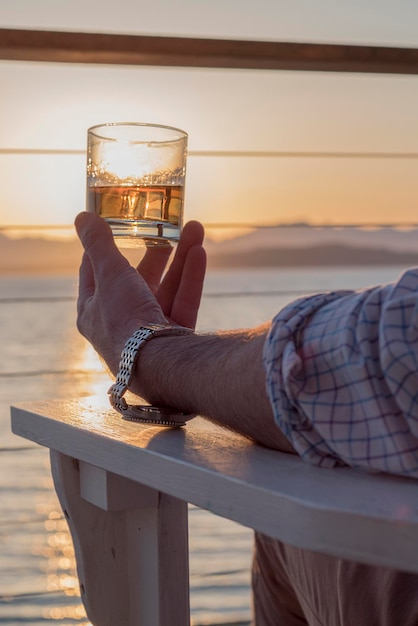 Photo man holding glass of beer at sunset