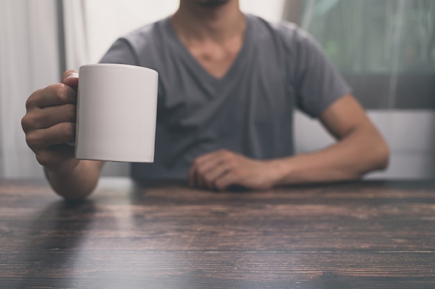 사무실에서 책상 위에 물 한 잔, 커피잔을 들고 있는 남자.