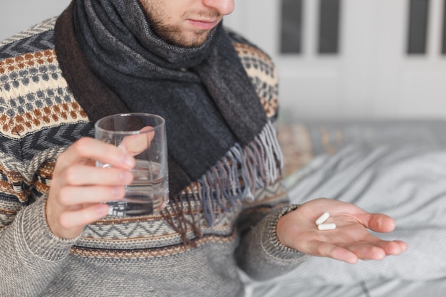 水と薬のガラスを保持している男