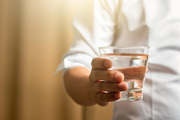 Foto uomo che tiene un bicchiere d'acqua uomo che beve un bicchiere d'acqua dopo il lavoro un bicchiere d'acqua mano femminile che tiene una tazza di vetro