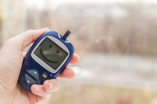 Photo man holding glucometer with test strip with smile on the monitor