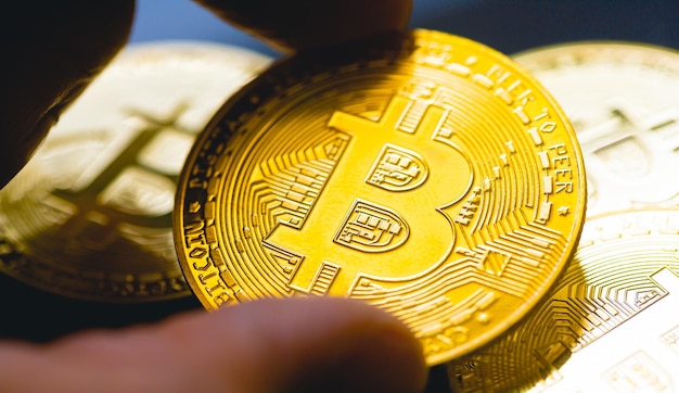 A man holding a gold coin of Bitcoin in macro photography