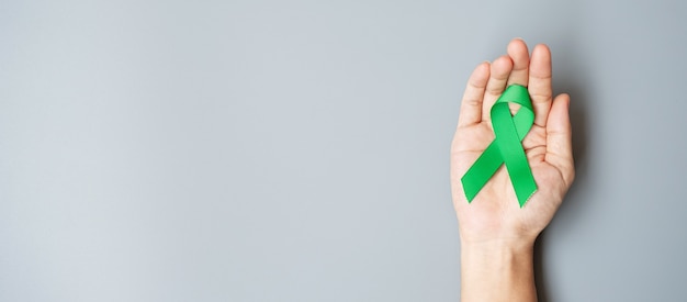 Man holding green Ribbon for supporting people living and illness.