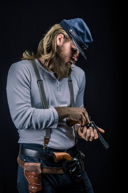 man holding gun while standing against black background