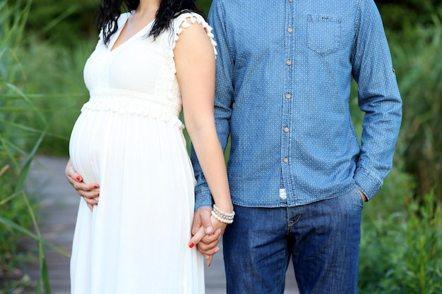 Photo man holding hands of pregnant woman while standing at park