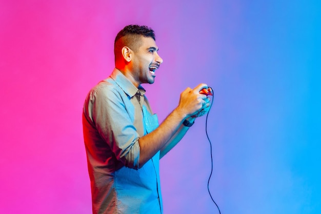 Man holding in hands red gamepad joystick grimacing playing video games with happy expression