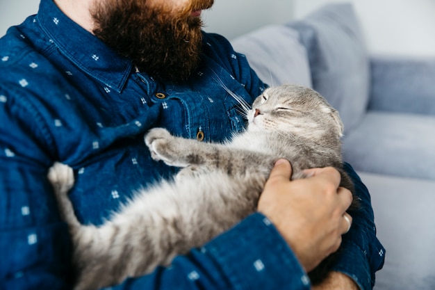 眠っている猫の手を握って男