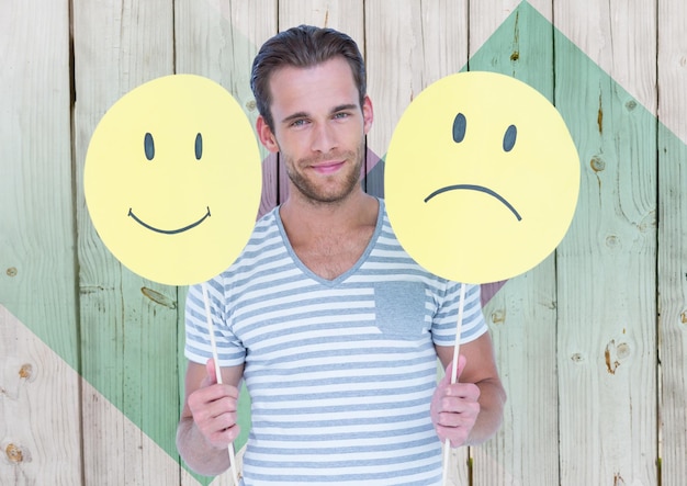 Man holding happy and sad smiley faces