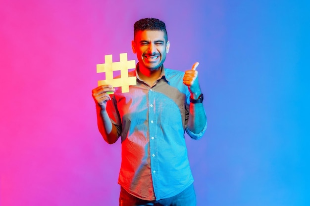 Man holding hashtag symbol showing thumb up recommending popular topics internet trends