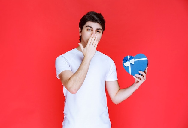 Man holding a heart shape gift card and thinking. 