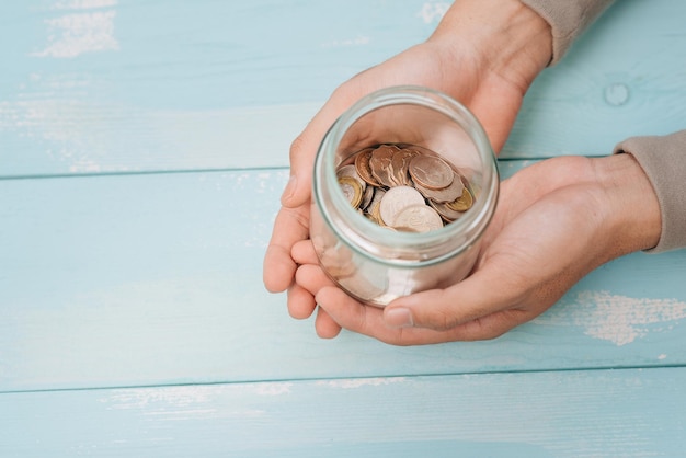 Man holding his piggy bank money account in his hands in a glass jar