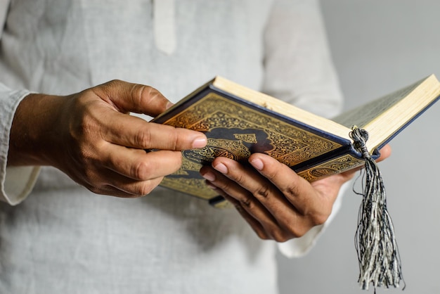 A man holding a holy book with the title al quran on it.