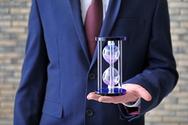 Man holding hourglass on blurred background