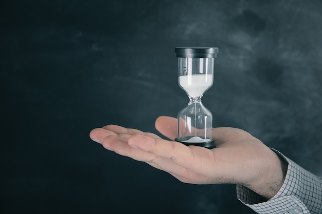 Man holding an hourglass in his hand .