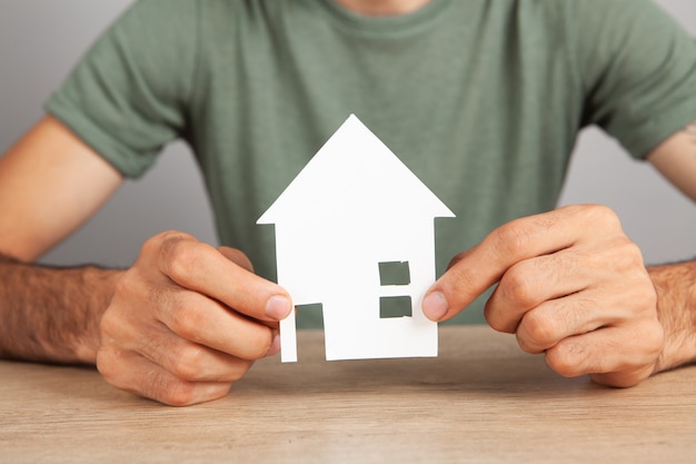 A man holding a house by the table