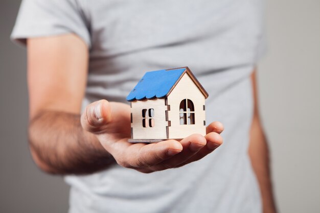 Man holding house on gray background