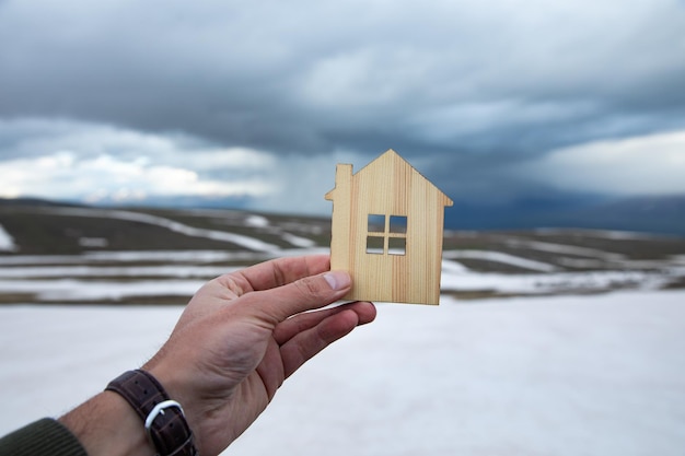 Man holding house model on snowy landscape