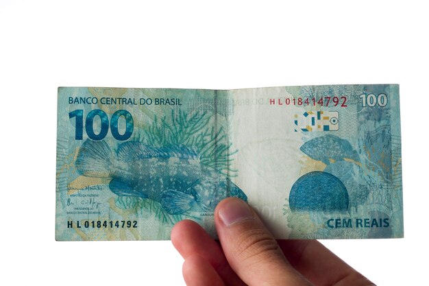 Photo man holding hundred reais bills isolated on white. brazilian money.