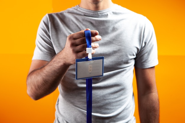 Man holding ID tag on orange background