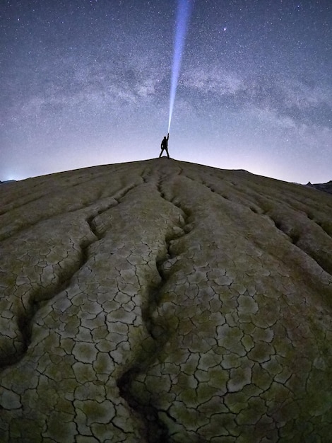 Foto uomo con una torcia illuminata in piedi sulla montagna contro il cielo
