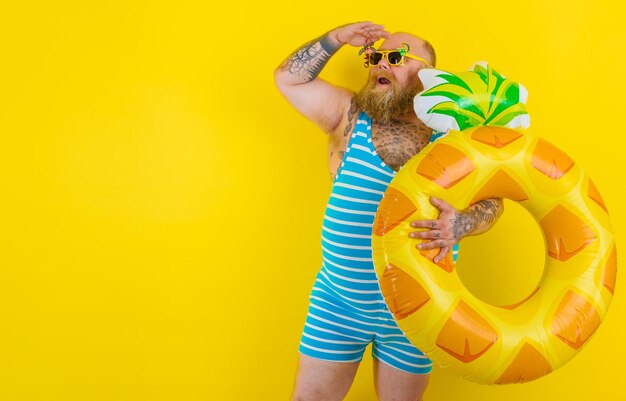 Man holding inflatable ring while standing against yellow background
