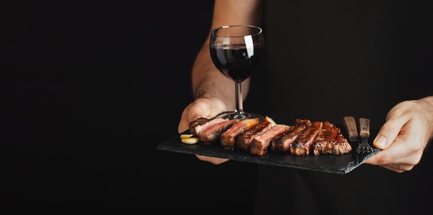 Man holding juicy grilled beef steak.