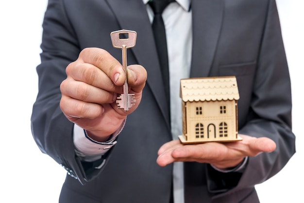 Man holding key and wooden house model