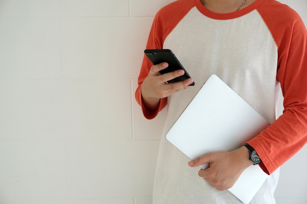 Man holding laptop computer and using smart phone