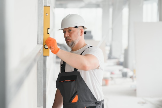 Man holding level against plasterboard interior drywall Attic renovation