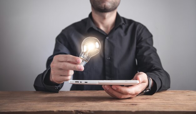 Uomo che tiene la lampadina con un tablet. ispirazione, tecnologia, creatività, affari