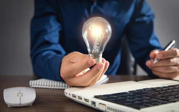 Man holding light bulb and working at office