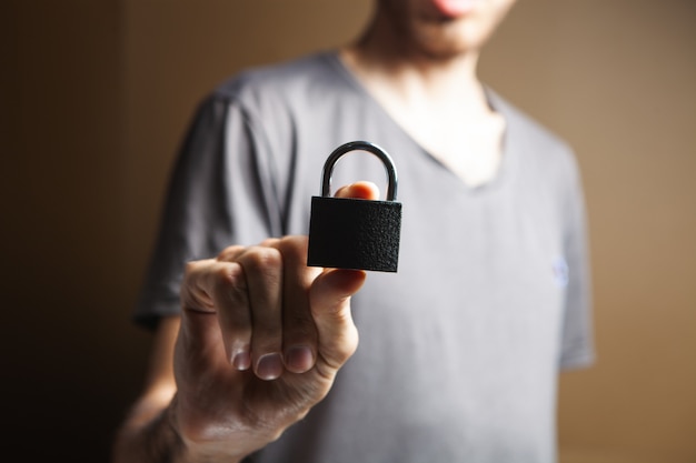 A man holding a lock in his hand on brown background