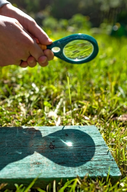 木に焦点を当てた火を作る虫眼鏡を持っている男