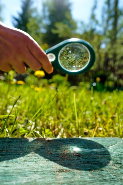 Man holding a magnifying glass making fire focused on wood