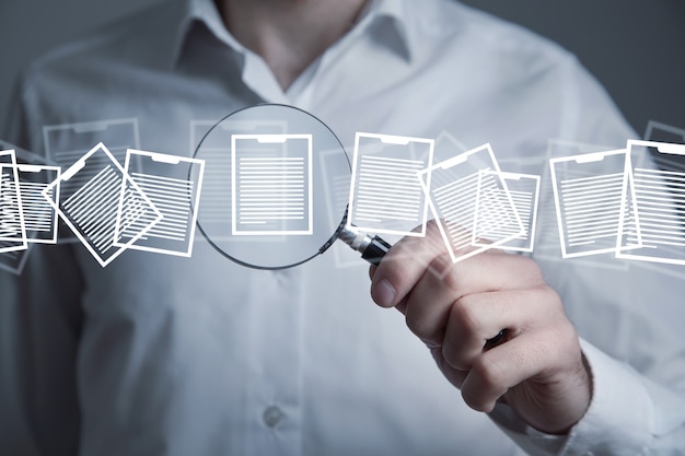 Man holding magnifying glass with a documents.