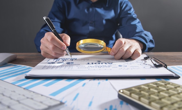 Man holding magnifying glass with a graphs and charts. Business. Analysis