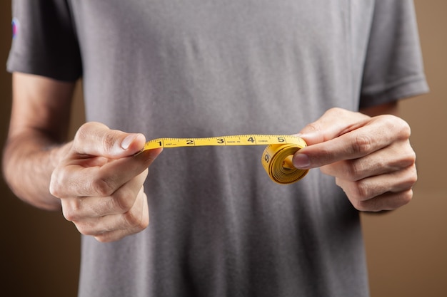 Man holding a measuring tape on brown background